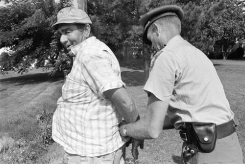 10244271 - Mississippi Highway Patrolman handcuffs one of two men arrested in Goldwater, Mississippi, June 8, 1966 near the marchers who took up James MeredithÂs March to Jackson, Miss. The unidentified man above was a passenger in a truck which had been driven from a side street across the line of march and stopped. (AP Photo)