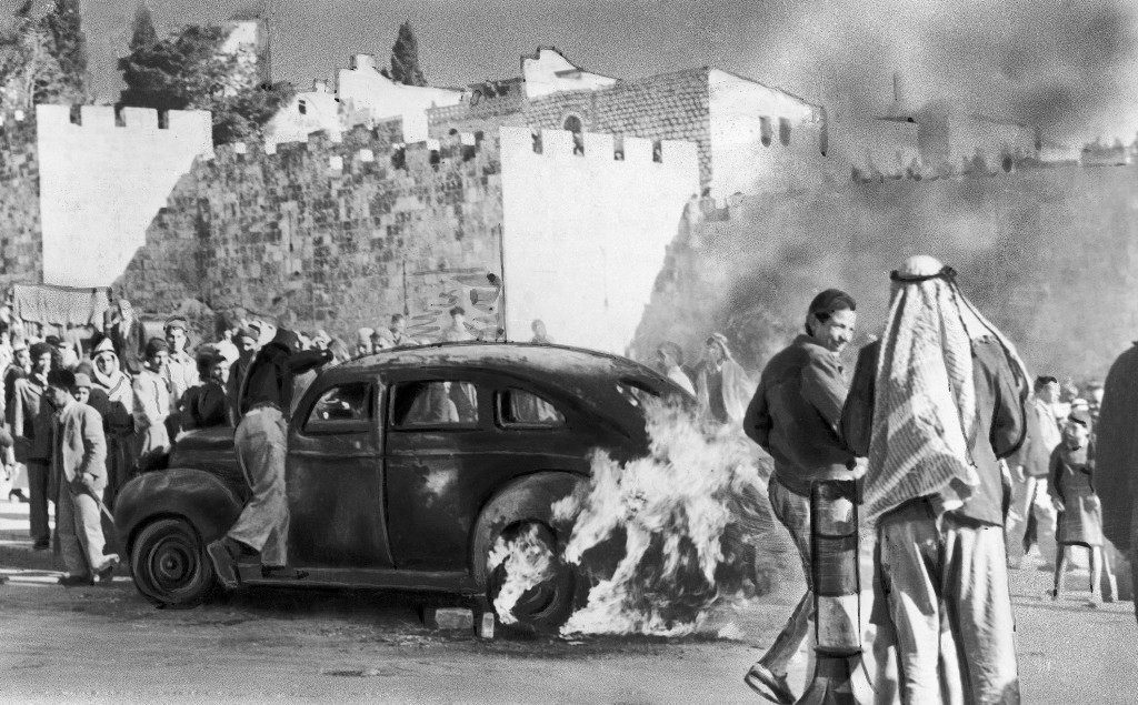 A Jewish cab is set ablaze by an angry mob near the Damascus Gate in Jerusalem, Israel on December 29, 1947 after Jews shooting from a taxi assassinated 15 persons, among them 12 Arabs, 2 British constables and a Jew. (AP Photo) Ref #: PA.10005928  Date: 29/12/1947 