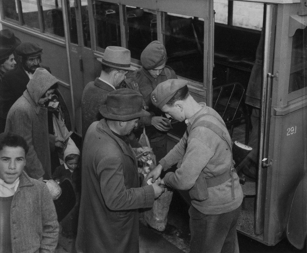 Members of the Royal Irish Fusiliers go through personal belongings and identification papers as passengers of a bus halted, Feb. 2, 1947 at a road block on the main highway between Jerusalem and Tel Aviv. (AP Photo) Ref #: PA.18363261  Date: 02/02/1947