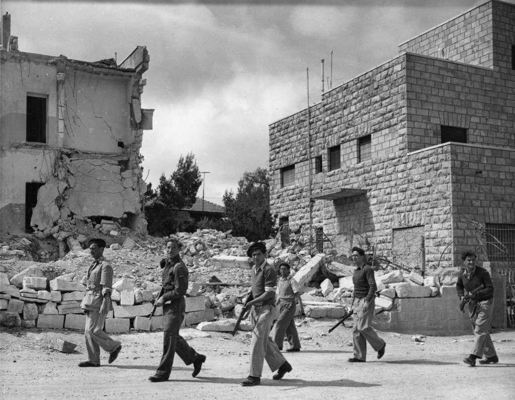 Jewish Haganah troops are seen on ppatrol near the no-man's-land line in Katamon, a suburb of Jerusalem, Palestine May 6, 1948. In the back left is the Arab owned hotel Semiramis, by bombed by Haganah forces four month ago, with the argument that it was used as an Arab headquarter for commanders of the fighting Arabs. 15 men and women were killed in the explosion. Katamon, once an Arab stronghold, was wrested from them by the Haganah forces in a three day battle ending May 4, 1948. There was a continuous battle with automatic weapons and armoured cars. Except for the Haganah gurds and patrols all the former residents have departed. (AP Photo/Pringle) Ref #: PA.5737133  Date: 06/05/1948