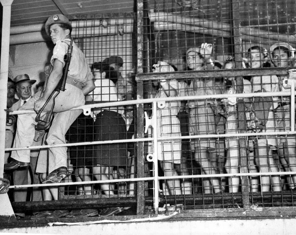 British soldier, armed with a sten gun, on guard near the cages of orphaned Jewish children, as they prepare to leave a ship to live in Haifa, Palestine, Aug. 21, 1947. Five hundred orphans, the majority of whom lost their parents during World War II, were interned in Cyprus and brought to Palestine as part of the monthly immigation quota. (AP Photo/Pringle) Ref #: PA.5737162  Date: 21/08/1947