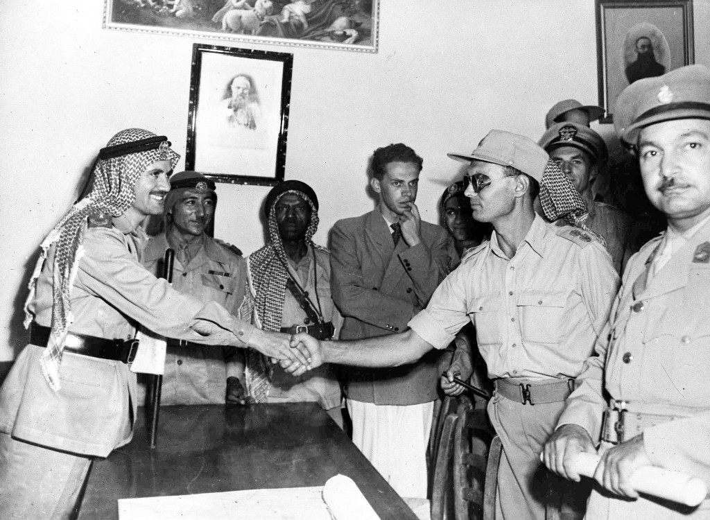 Commander of Israel's Jerusalem Brigade, Colonel Moshe Dayan, right, and Arab Legion Commander Abdullah Bey El-Tel, shake hands after a conference in a monastry in Jerusalem's no-man's land, Aug 22, 1948. Facing camera right, is Lieutenant Colonel Ahmed Abd Aziz, commander of the Egyptian forces in the southern section of Jerusalem. A few hours after this picture was taken Colonel Aziz was ambushed and killed. (AP Photo/Pringle) Ref #: PA.5737197  Date: 22/08/1948