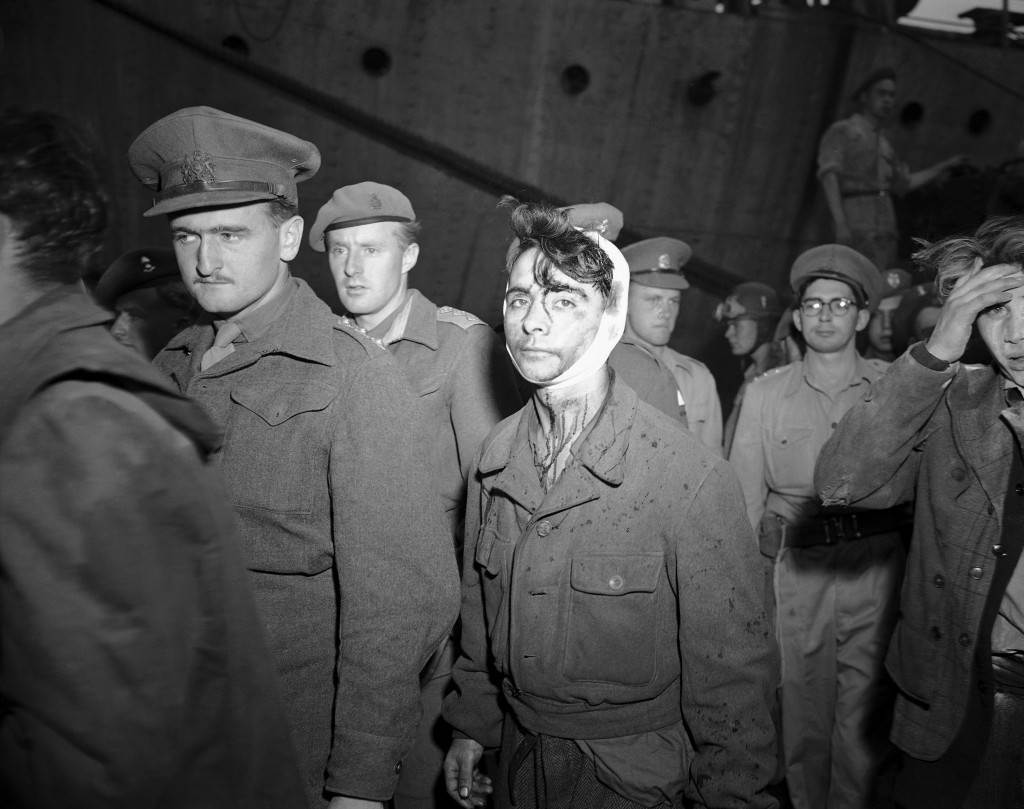 A young Jewish boy, wounded and bloody after the fight with British soldiers on board the refugee ship Knesset Israel, passes a line of soldiers to board the troopship Empire Heywood on Dec. 4, 1946 in Haifa, one of three vessels on which passengers from the refugee ship were deported. (AP Photo) Ref #: PA.7090686  Date: 04/12/1946