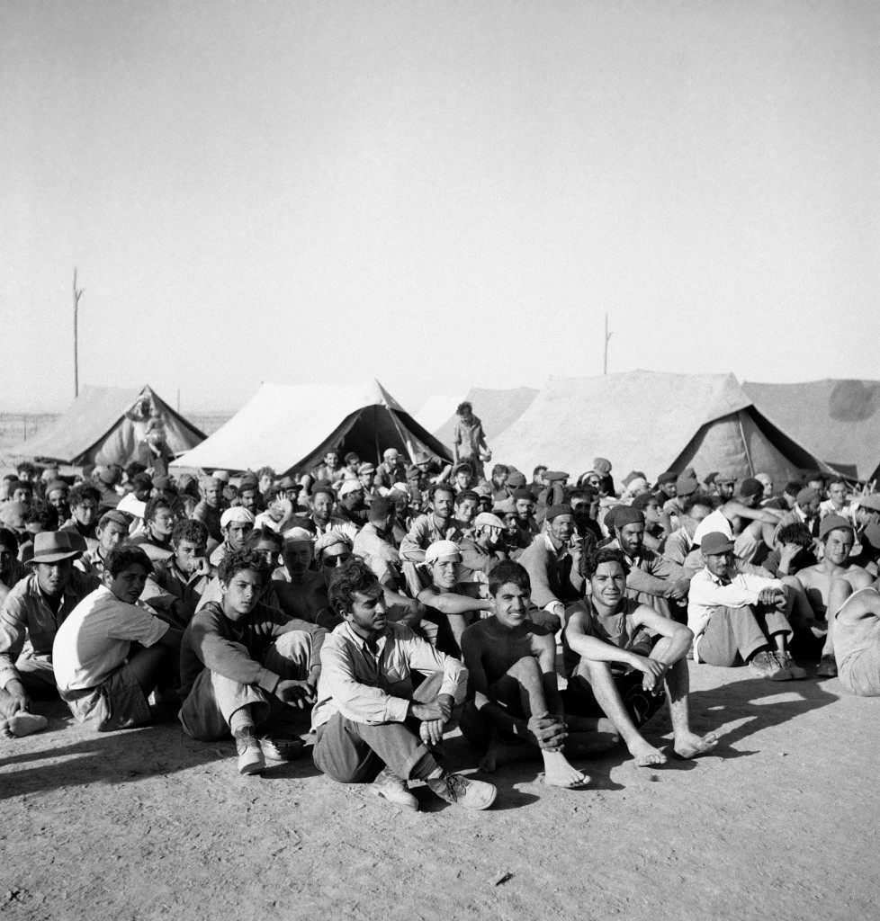 Joshua Cohen, 12, one of nearly 300 prisoners taken by Trans-Jordan Legion on surrender of Old City Jewish quarter, Jerusalem, 28/5 and now held in Trans-Jordan. He is seated on the ground with other prisoners for sunset check by Legion guards on June 4, 1948 in Trans-Jordan. (AP Photo/ Daniel De Luce ) Ref #: PA.7091311  Date: 04/06/1948