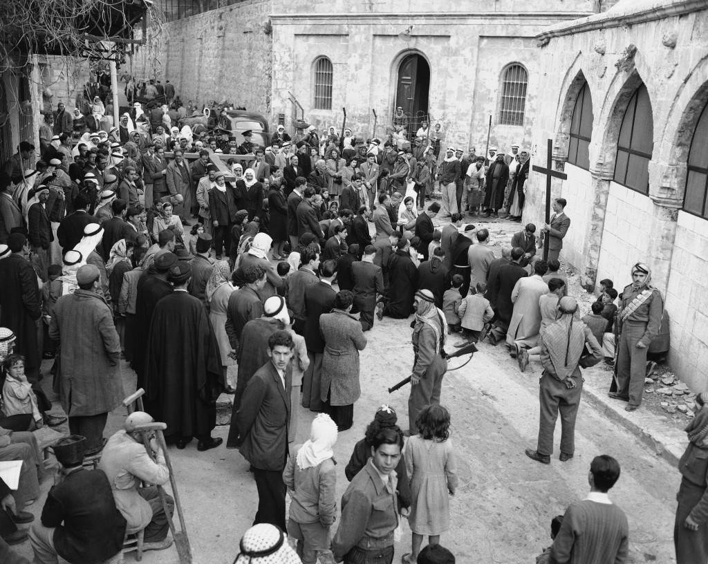 Christian Arabs, carrying a huge cross, reach the third station of the Cross in Jerusalem on March 26, 1948 as they retrace the path of Jesus Christ from the court of Pontius Pilate of Calvary, others kneel on the spot, where it is believed Christ Fell for the first time under the burden of the cross. Photo received in New York, March 26, by radio from London. (AP Photo) Ref #: PA.7380118  Date: 26/03/1948