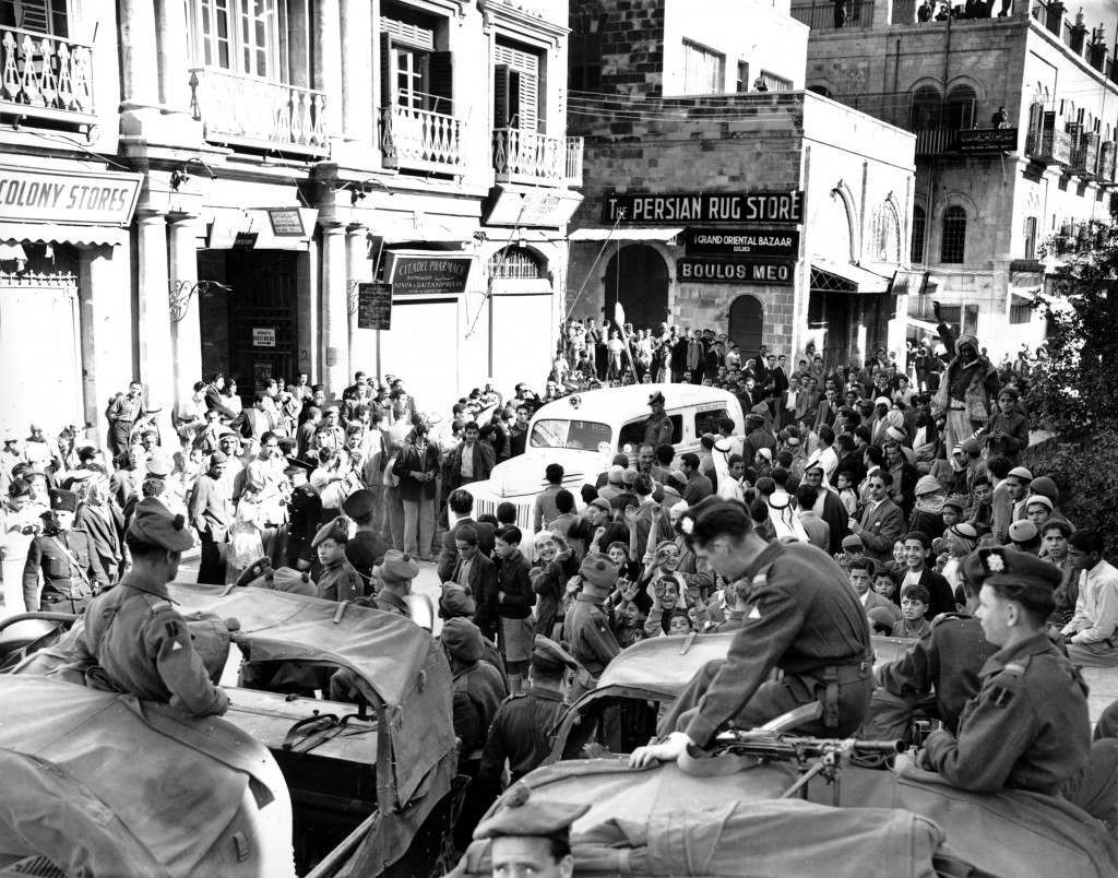 A white Jewish ambulance, with a British soldier riding aboard, carries wounded Jews through a crowd of Arabs at Jaffa Gate in Jerusalem as British soldiers keep watch in Dec. 1947. The Arabs, who were imprisoned inside Jerusalem's Old City during curfew hours, did not attack the ambulance. (AP Photo/James Pringle) Ref #: PA.8669141  Date: 01/12/1947