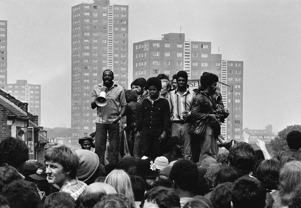 Darcus Howe (with loudhailer) addresses a crowd from on top of a toilet block, 1977.