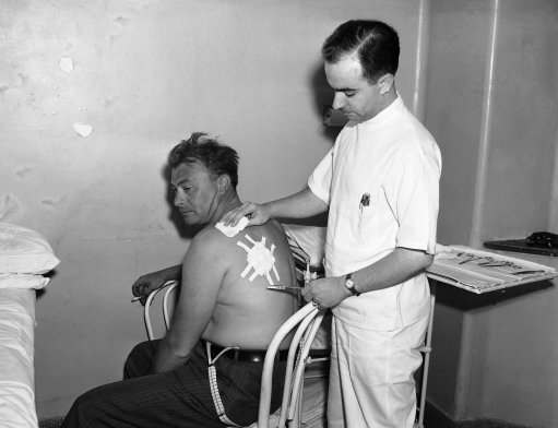 New York City detective Frederick Morelock has his left shoulder patched up at flushing hospital on July 5, 1940, after a piece of metal from a bomb which exploded on July 4 at the New York world?s fair tore into his flesh without his feeling it. Morelock was in the group of policemen removing the bomb from the British Pavilion and had stepped away to report to a superior when the bomb went off killing two policemen and injuring four others. He said on July 5, he didn?t know he had a wound until he took off his shirt.