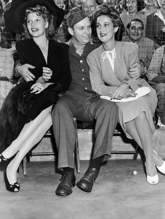 Dressed in the uniform of a technical sergeant of the U.S. Army Air Forces which he joined, Gene Autry, cowboy movie actor, found himself as popular with a pair of glamorous actresses as he is with the kids of the nation when he appeared at a benefit party staged by film actress Marion Davies, Aug. 9, 1942. With him are Rita Hayworth, left, and Dorothy Lamour. (AP Photo)