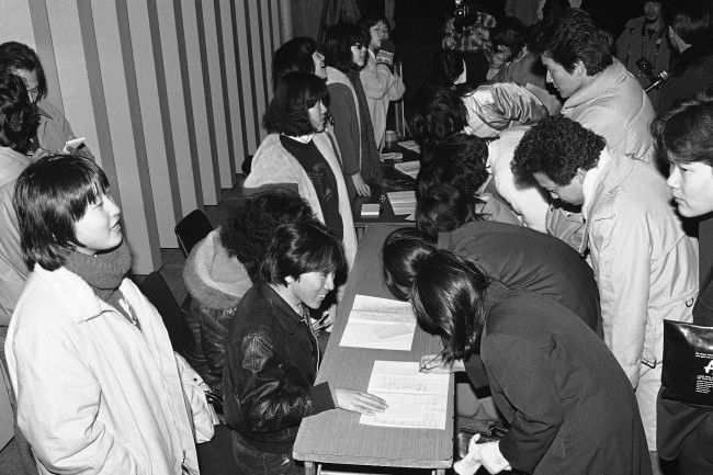 Members of Tokyo Fan Club of Wings left, collect signatures from young rock enthusiasts outside the Budokan Hall, where the British rock group was to give its first concert in Tokyo on Monday, Jan. 21, 1980. The concert was canceled because its leader Paul McCartney was arrested last week for Marijuana possession. The fans, who came to the hall for a refund, were willing to sign their names at the request of the fan club, which said it intended to give the signed note book to McCartney to comfort him. (AP Photo/Sadayuki Mikami)