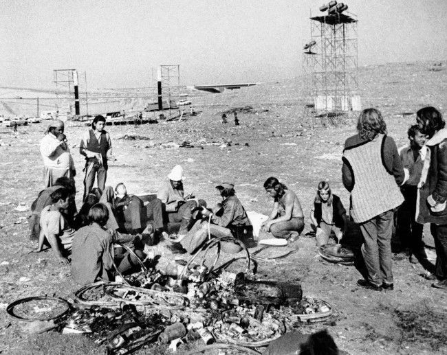 Some rock music fans still play, cook and relax in the aftermath of yesterday's free concert at the Altamont Speedway near Livermore, Dec. 7, 1969. In the background the frameworks of the stage and light stands are visible. The free concert, already dubbed Woodstock West, attracted more than 300,000 people. (AP Photo) 