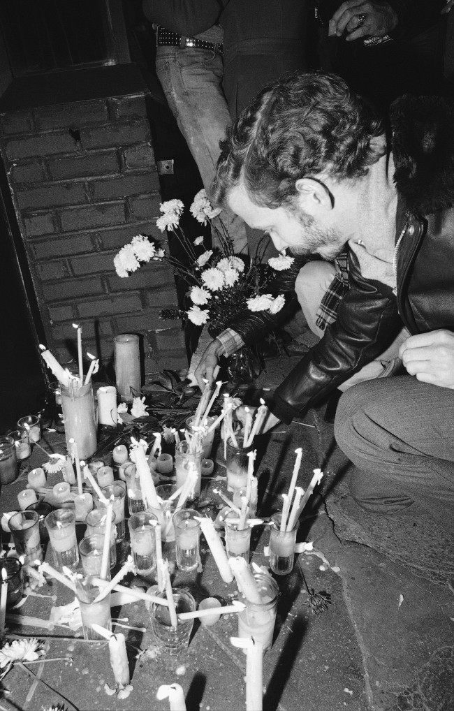 A man places a memorial candle on the sidewalk in front of the Ramrod Bar in New York, Nov. 20, 1980 on the spot where two people were killed and seven others injured in a shooting incident on Wednesday. A former New York transit police officer was arrested and charged with the murders.