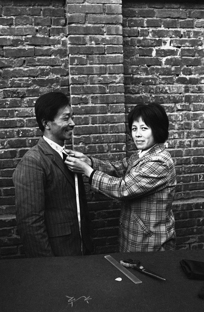 A Chinese woman tailor, one of nearly 70 who practice their trade on Democracy Street in Lanzhou, fits a customer for "western" garments in an open air stall, Nov. 14, 1980. Lanzhou is the capital of Gansu province far to the west of Peking. 