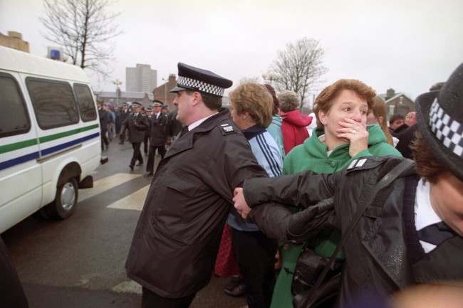 ANGUISH SHOWS ON THE FACE OF A YOUNG WOMAN BEHIND POLICE BARRIERS AS THE CONVOY CARRYING THE TWO-TEN-YEAR OLDS CHARGED WITH THE MURDER OF JAMES BULGER LEAVES SOUTH SEFTON MAGISTRATES COURT. 3/4 OF PEOPLE GASPING BEHIND THE BLUE LINE AS THE VAN PASSES BY.  Date: 22/02/1993