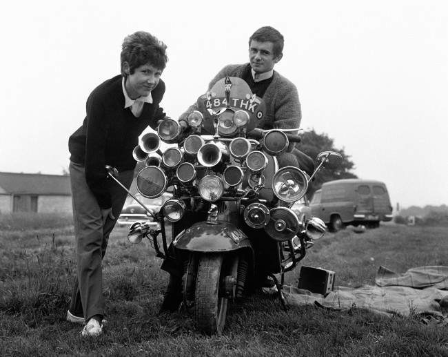 The modern fad for having as much sound and light as possible on your scooter reached the Epsom Downs for Derby Day. Proud owners are Roy Young and Linda Jarvis. Proud riders are Roy Young and Linda Jarvis at Derby Sunday on the Epsom Downs. Date: 31/05/1964