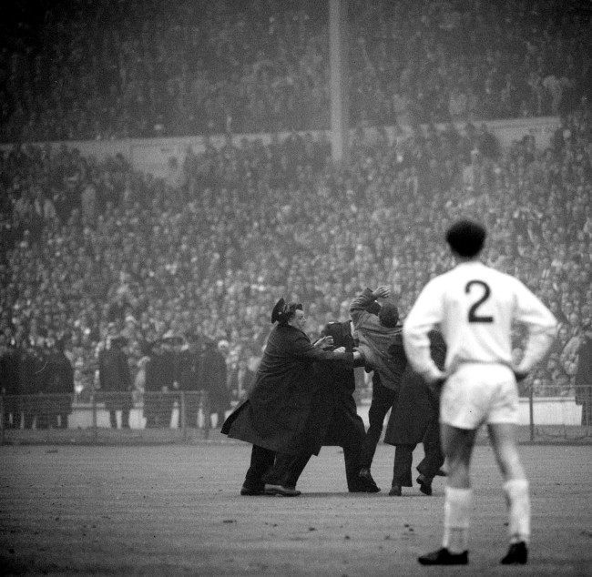 An excited fan, who rushed onto the pitch after Liverpool had scored their second and winning goal, is carried from the field by policemen during extra time