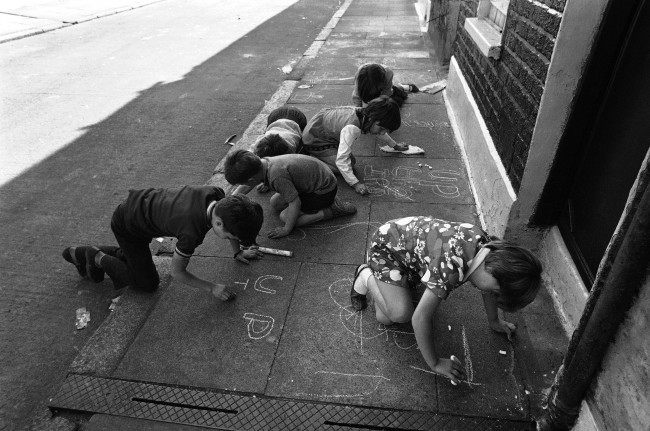 Small children drawing pro Irish Republican Army notes with chalk on the pavement, such as Up the IRA, in Lecson Street in Belfast, Northern Ireland on August 17, 1971. (AP Photo/Peter Kemp)