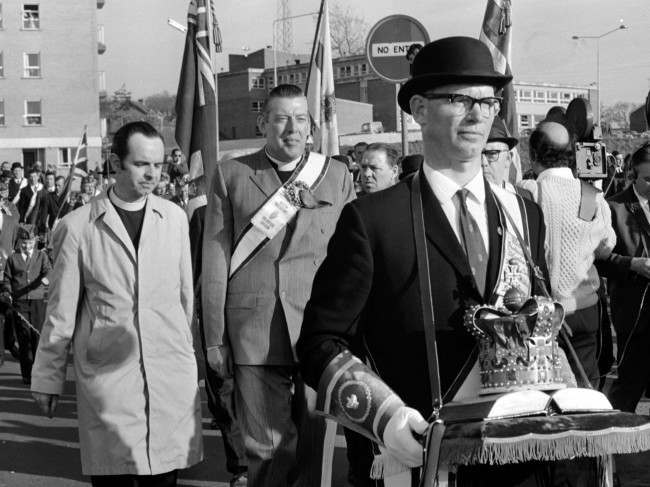 Protestant leader Reverend Ian Paisley, behind crown bearer, leads the Protestant Easter March through Armagh, Northern Ireland, while British troops stand guard on Easter Saturday, April 10, 1971. 