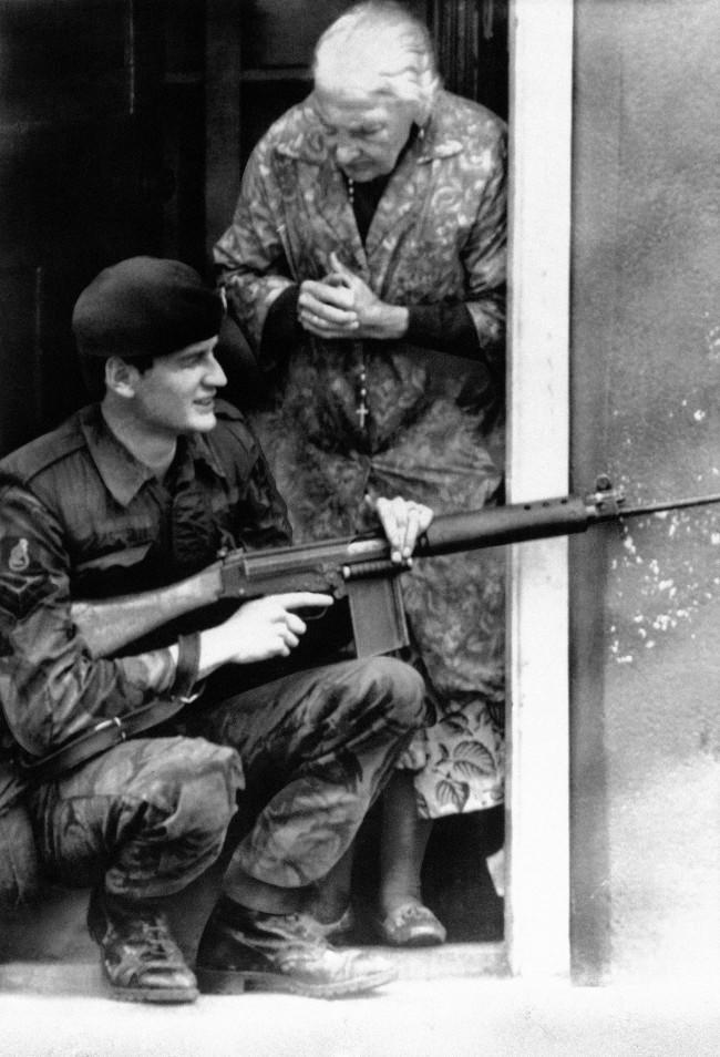 An old woman, a rosary dangling from her neck, clasps her hands on finding a British Army sharpshooter on her door step in BelfastÂs market area as troops flushed out snipers barricaded in bakery in Northern Ireland capital on August 11, 1971. (AP Photo)