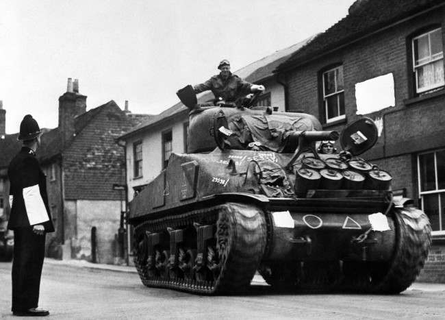 A British Army Sherman Tank rumbles down a street on its way to a south coast port prior to the Normandy landings of 6th June 1944 (D-Day). The wartime Censor has obliterated a sign in the background as well as the tank's unit markings.