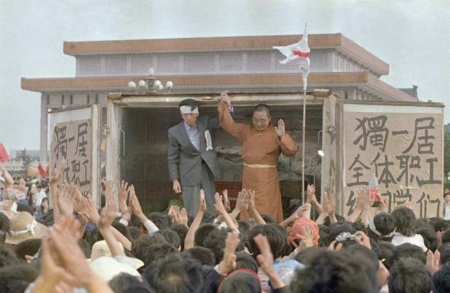Li Nan, left, of Du Yiju Restaurant, and Yuan Chi, a monk with the China Buddhist Association, receive cheers from students in Tiananmen Square, Sunday, May 21, 1989, Beijing, China. They have donated over $53,000 worth of food to the protestors in the square. (AP Photo/Mark Avery)