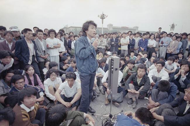 Beijing University students listen as an unidentified strike spokesman details plans for a rally in Tiananmen Square, which they have occupied for the last two weeks, Sunday, May 28, 1989, Beijing, China. (AP Photo/Jeff Widener)