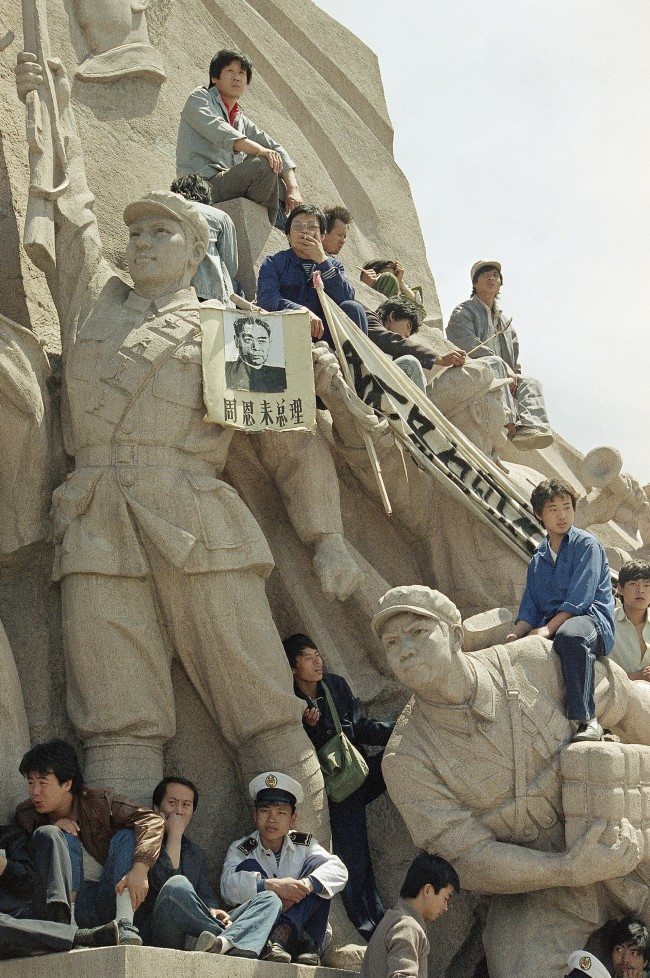 Beijing University students use a monument to the late chairman Mao Tse-Tung at his tomb in Tiananmen Square to press their case for democratic reforms in Beijing, Friday, May 19, 1989. The picture hanging on the statue is the late Premier Chou En-Lai. (AP Photo/Sadayuki Mikami) 
