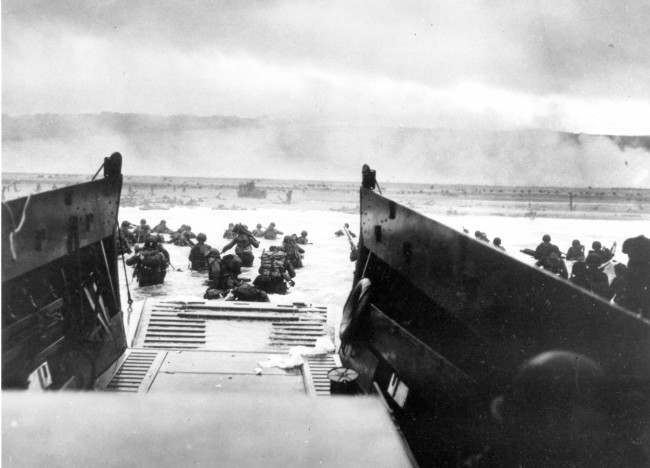 Under heavy German machine gun fire, American infantrymen wade ashore off the ramp of a Coast Guard landing craft on June 6, 1944, during the invasion of the French coast of Normandy in World War II.