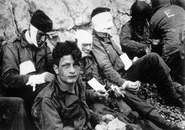 Men of the American assault troops of the 16th Infantry Regiment, injured while storming a coastal area code-named Omaha Beach during the Allied invasion of the Normandy, wait by the chalk cliffs at Collville-sur-Mer for evacuation to a field hospital for further treatment, June 6, 1944. (AP Photo)