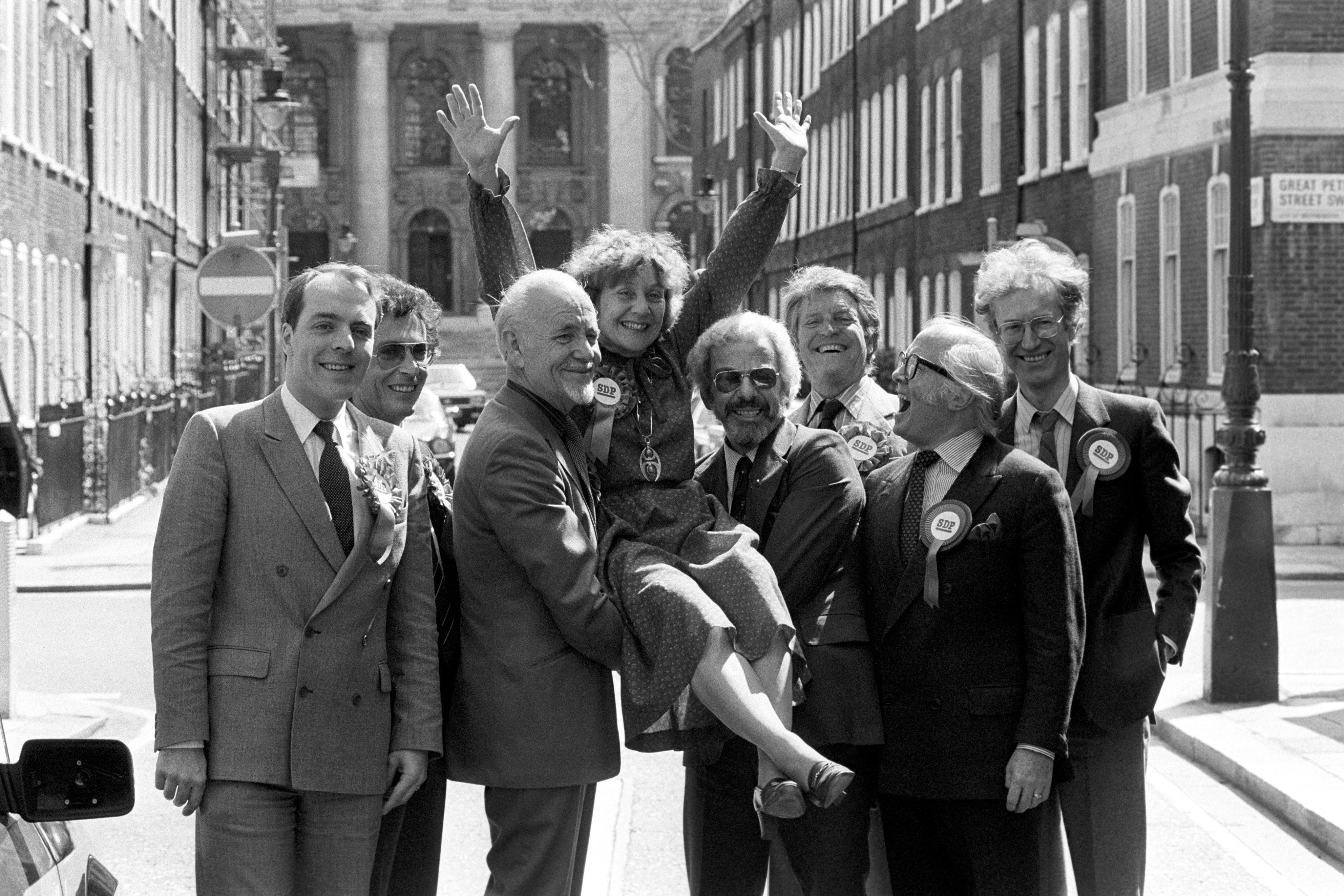 Mrs. Shirley Willaims, President of the Social Democratic Party, appears to be receiving support from the stars at SDP headquaters today. L-R: Simon Cadell, Robert Powell, Steve Race, Barry Cryer, Denis Quilley, Sir Richard Attenborough and Bamber Gascoigne. 11/5/1983