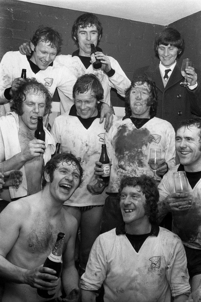 Hereford United players, including goalscorers Ronnie Radford (top l) and Ricky George (centre l), celebrate victory with a drink in the dressing room