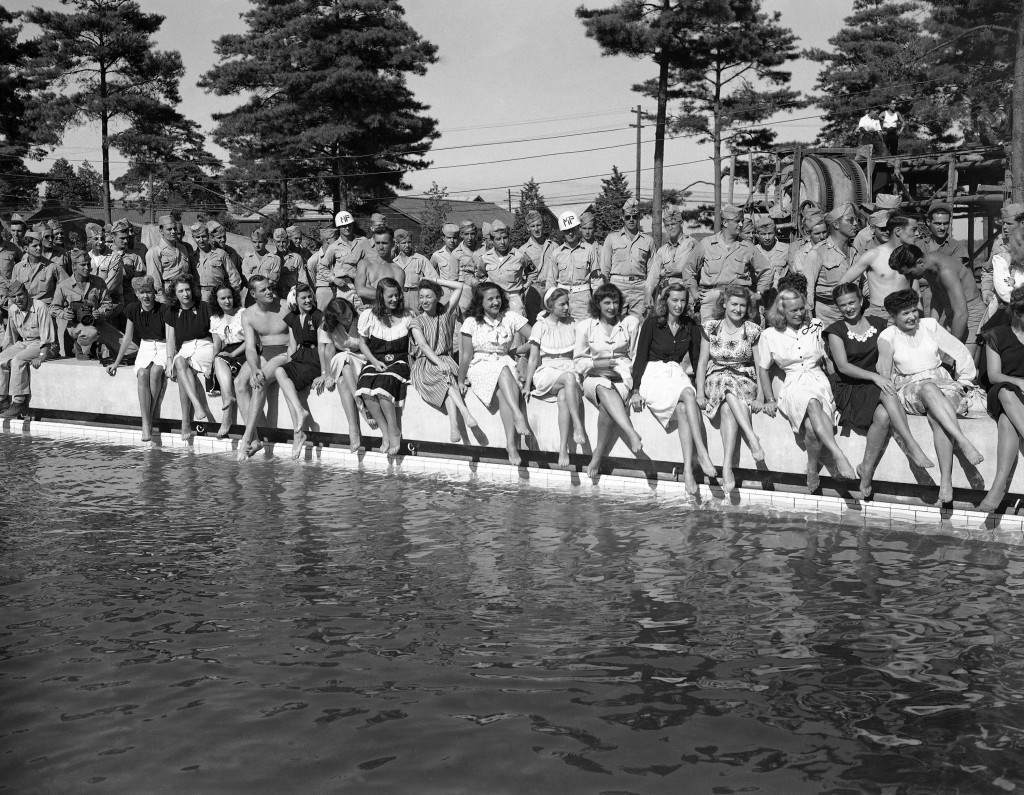 Show girls from the Mikado theater in Tokyo, their legs crossed and bare feet dangling near the water, pose on the side of a swimming pool at a new American air base at Yokota, Japan on August 17, 1946. How one male, presumably a soldier, got into the otherwise all-girl lineup at poolÂs edge was not explained. Uniformed soldiers stand behind the girls. (AP Photo/Charles Gorry) Ref #: PA.11560047 