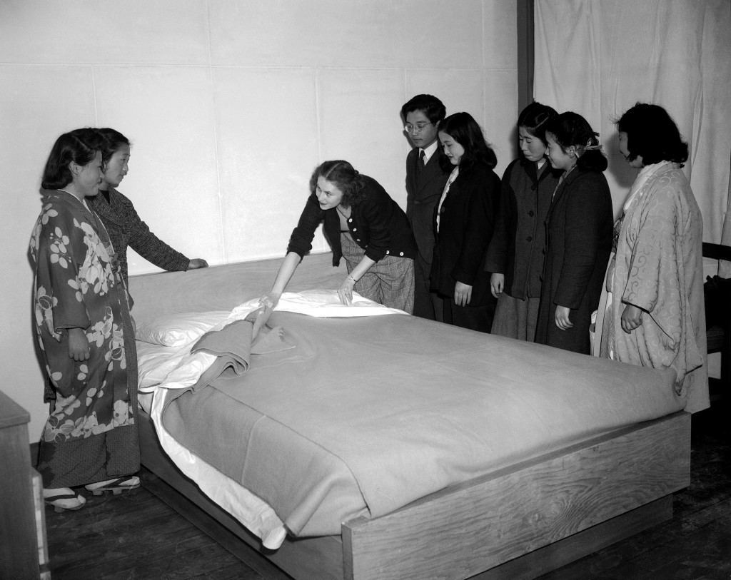 Although given preliminary instructions the girls are a bit vague about the proper making of a bed. Mrs. Anderson, with the help of an interpreter attached to the liaison section for the housing development, demonstrates the American way of bed making in Tokyo, Japan on April, 14, 1947. (AP Photo) Ref #: PA.11607761 