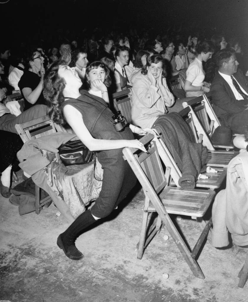 This unidentified teenager found Elvis Presley "too much" when he appeared at the Arena in Philadelphia, April 6, 1957. The girl matched gyrations in her seat with the gyrations of Presley on the stage. Her companion appears a little amazed. (AP Photo) Ref #: PA.2373268  Date: 06/04/1957 