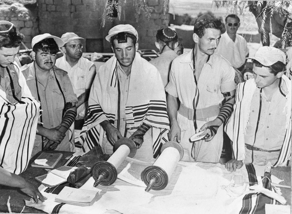 Orthodox Jews of the Israeli Army read the Torah of Holy Scrolls, during commemorations of the Jewish fast day Tisha Bav, in Tel Aviv, Israel, Aug. 19, 1948. The Jewish signs of mourning, "Tvilum" around the arms and on the forehead, are worn by the men and those who are also married wear shawls. (AP Photo) Ref #: PA.5755037 Date: 19/08/1948 