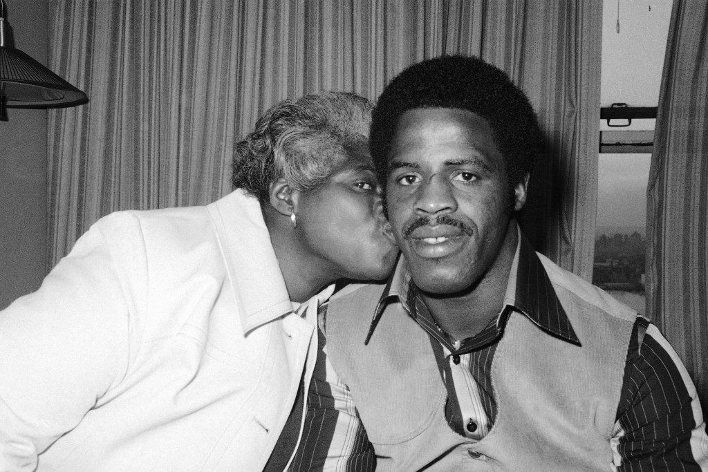 Earl CampbellÂs mother, Ann, plants a kiss on cheek of her son as the Texas football star waits in his New York hotel room to attend the Heisman trophy award dinner, Thursday Dec. 8, 1977. Campbell, who is going on to pro football as a certain first round draft choice, says heÂll take part of his pro money and buy a house for his mother who raises roses for a living. A widow, who has raised 11 children, Mrs. Campbell says she tried to discourage earl, Âbut he always loved football.Â (AP Photo) Ref #: PA.7333673  Date: 08/12/1977 