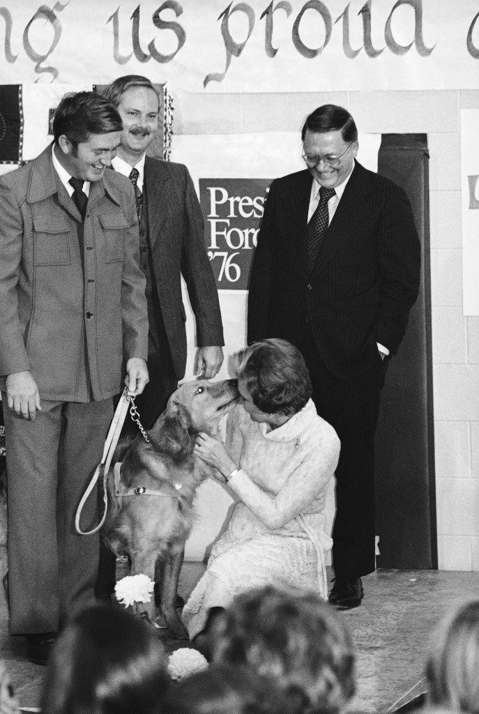 Jerry, a pup from the litter of President Gerald Ford and first lady Betty Ford's golden retriever Liberty, greets Mrs. Ford with a wet kiss on the face at a rally in a high school in Auburn Heights, Michigan, Oct. 28, 1976. Jerry was presented as a gift to the Leader Dogs for the Blind School in nearby Rochester, Mich., and presently is being trained there. (AP Photo) Ref #: PA.7684616  Date: 28/10/1976