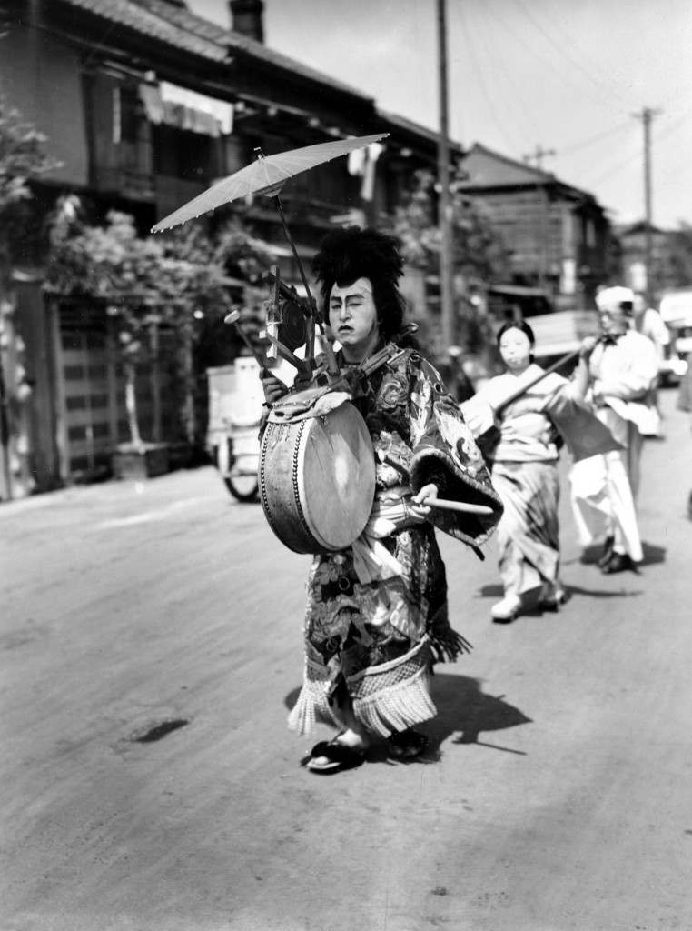 A Japanese man in costume beats the drum as he leads a musical parade of men and women who are walking advertisements featuring placards for restaurants through the streets of Tokyo, Japan, Feb. 14, 1947. (AP Photo) Ref #: PA.8661110 