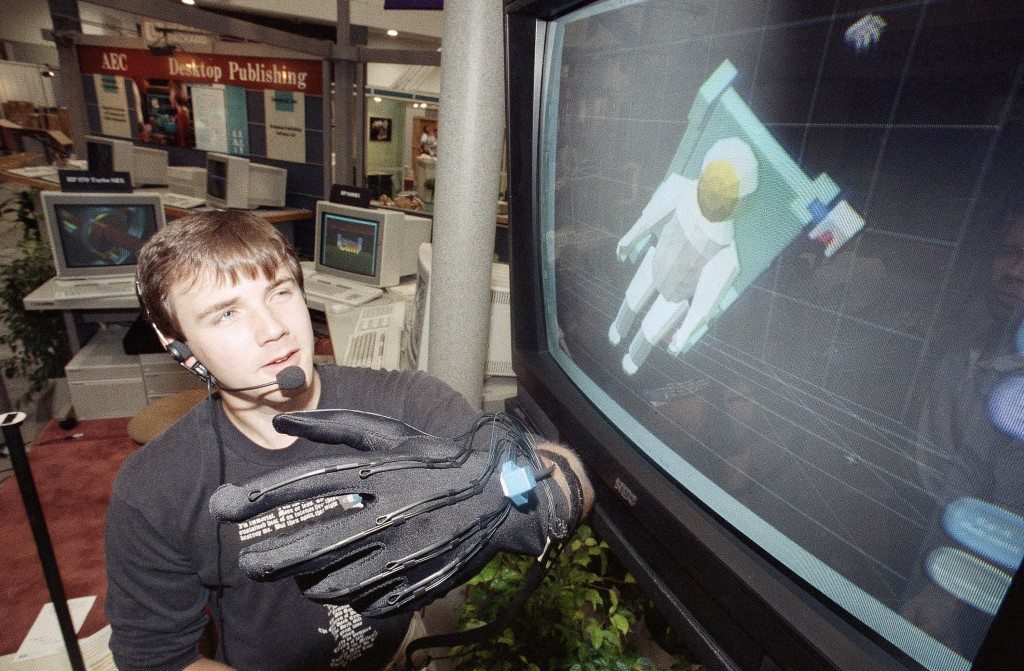 Chad Leeper of Hewlett-Packard shows how movements of his hand, recorded by fiber-optics and sensors on his glove, are used in a Sim Graphics Â“virtual realityÂ” system to control motions of the image of an astronaut on the computer monitor at right during a demonstration at the Siggraph computer graphics conference in Boston on July 31, 1989. A system like this could allow human operators to safely control robots working in hazardous environments, like space or inside nuclear reactors. (AP Photo/David M. Tenenbaum) Ref #: PA.9197080 
