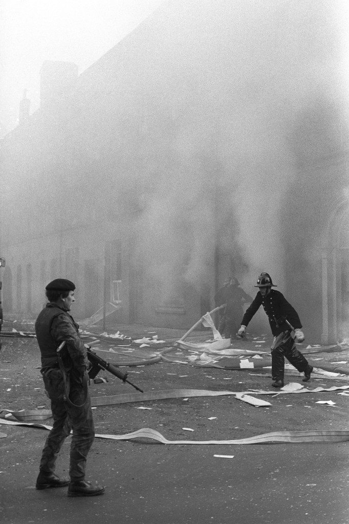 A British soldier guards firemen fighting a blaze after a bomb blast at a miller's beside the River Foyle in Londonderry, when bombers opened a new offensive in the city in response to the shooting deaths of 13 civilians at the weekend by British soldiers. Ref #: PA.12441676  Date: 03/02/1972