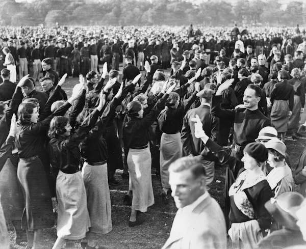 9th September 1934: Sir Oswald Mosley acknowledging fascist salutes from female members of the British Union of Fascists at an evening demonstration in Hyde Park.