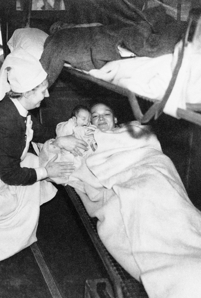A nurse hand a baby to its mother in an ambulance after, bombs had driven them from a London Hospital, Oct. 27, 1940.