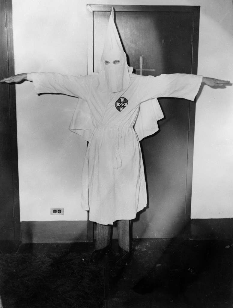 February 1947:  Stetson Kennedy, author of the Ku Klux Klan study 'Southern Exposure', posing in the Klan's uniform to illustrate the sign of the cross made before the altar at KKK meetings.  (Photo by Keystone Features/Getty Images)