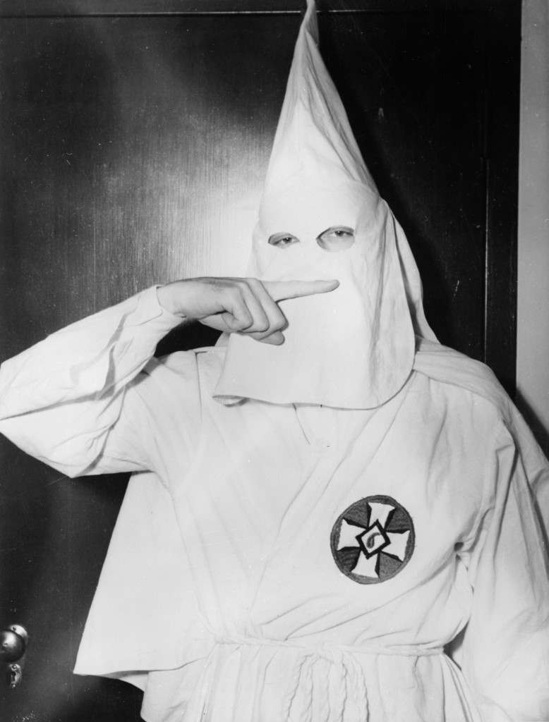 February 1947:  Stetson Kennedy, author of the Ku Klux Klan study 'Southern Exposure', posing in the Klan's uniform to illustrate the sign of the cross made before the altar at KKK meetings.  (Photo by Keystone Features/Getty Images)