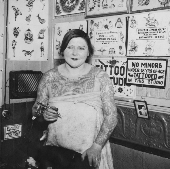 heavy-tattooed woman at a tattoo parlour, USA, circa 1930.