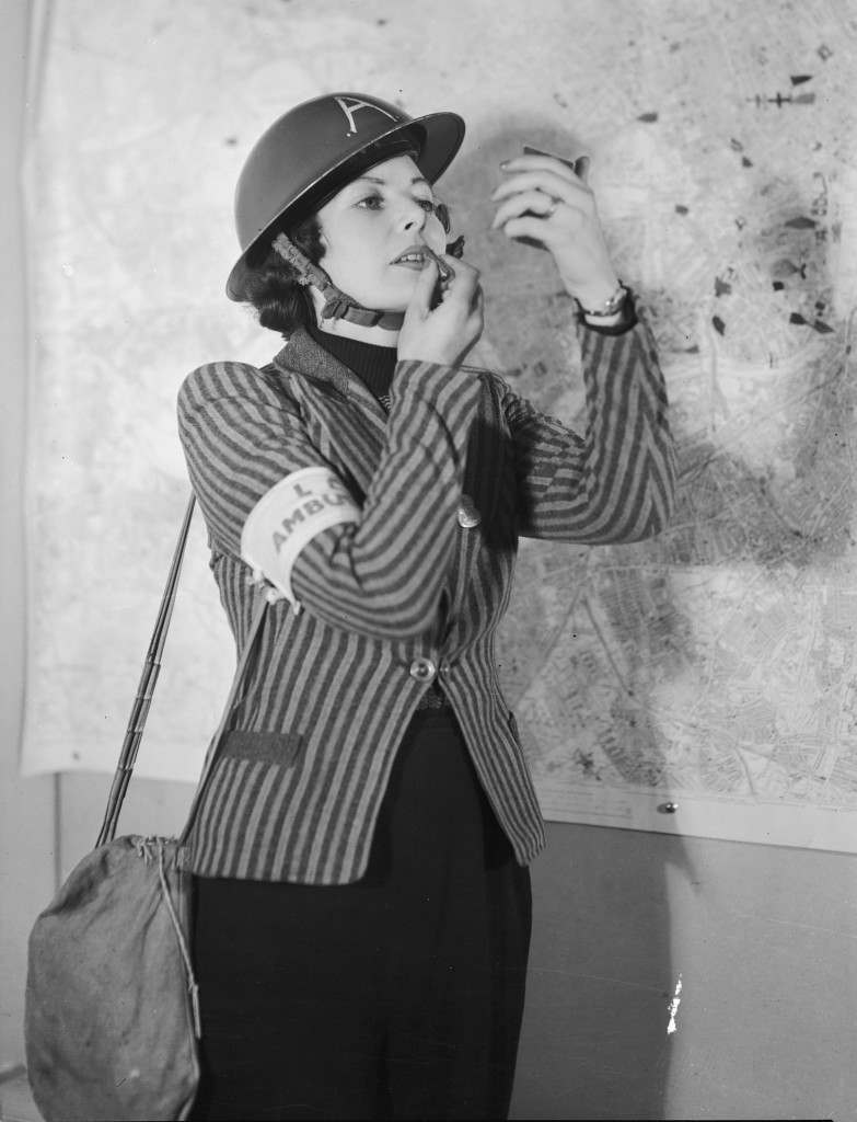 An ambulance worker in Kennington, London applies her lipstick, 1940.