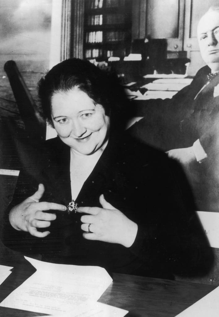 7th July 1941: Mrs Brigid Hitler, the wife of Adolf Hitler's stepbrother Alois, sitting at her desk at the British War Relief Society in New York City. She is pointing to her Aid Britain brooch. (Photo by Keystone/Getty Images)