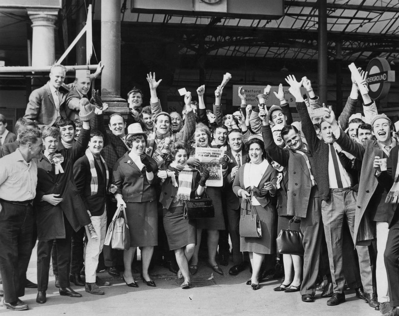 Liverpool fans at Euston Station, London, 1st May 1965.  They are on their way to see their team play Leeds United in the FA Cup final at Wembley. A woman (centre) is holding a copy of the Evening Standard newspaper with the headline 'Liverpool trying for cup double'. Liverpool later won the final 2-1. (Photo by Central Press/Hulton Archive/Getty Images)