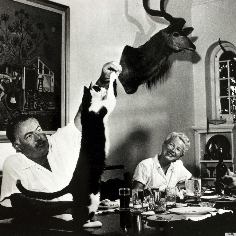 Literature Personalities. pic: circa 1940's. Author Ernest Hemingway watched by his wife Mary, feeds tit bits to the cat at dinner. Ernest Hemingway, (1899-1961) US writer of novels and short stories and Nobel Prize winner, also a keen sportsman. He was p