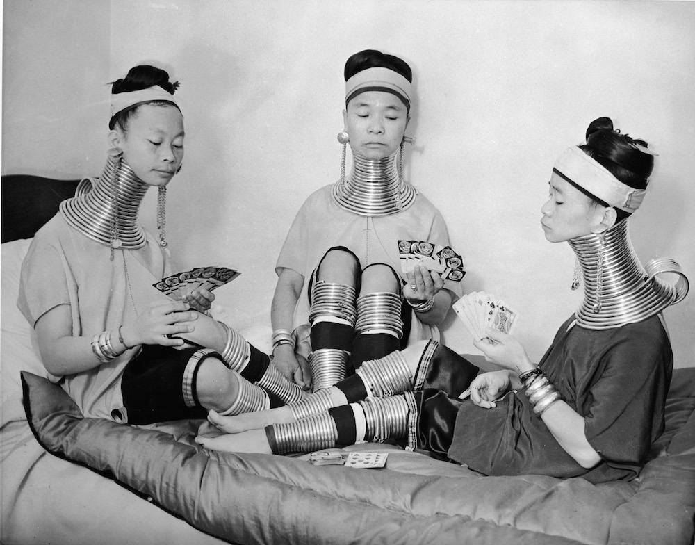 Three Burmese women members of a circus play cards as they wear the brass neck and leg rings traditionally worn by Padaung women since childhood and which cannot be removed, London, January 4, 1935. (Photo by Keystone/Getty Images)